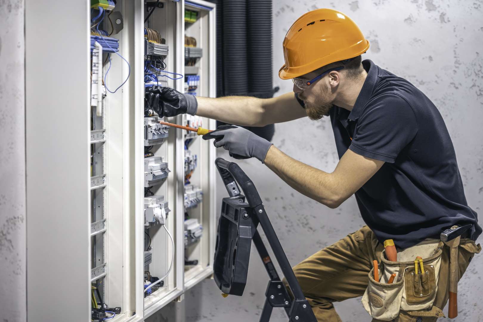 Young adult electrician civil engineer screwing equipment into fuse box. Controls System Engineering