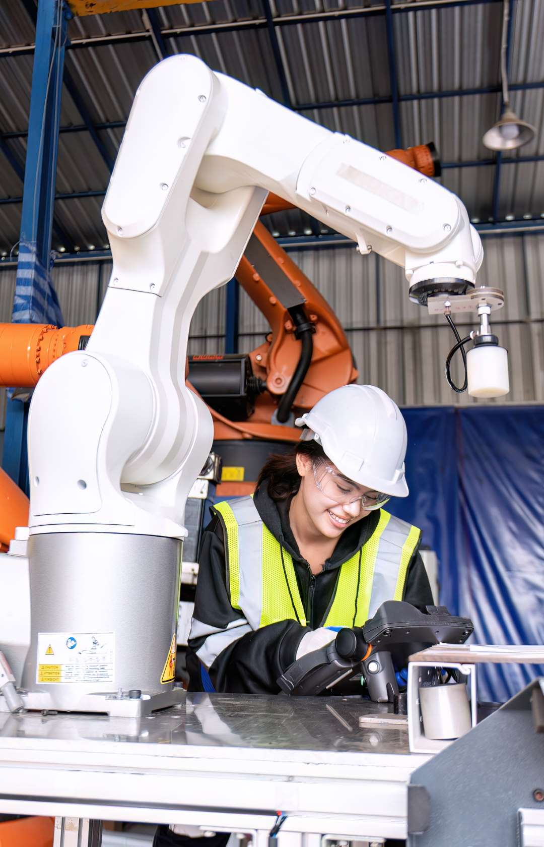 Young female asian service engineer holding robot controller operate robot arm automation factory Robotics Integration Services